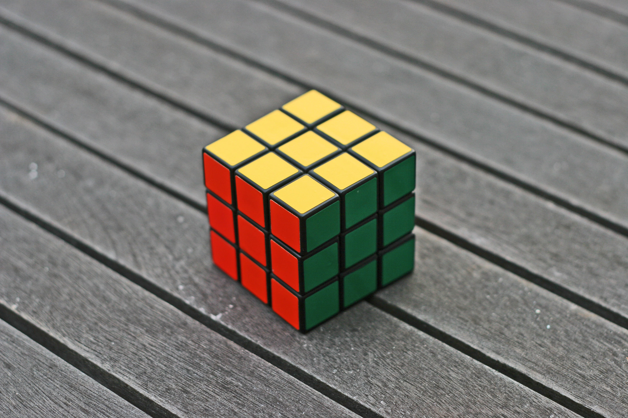 A Rubik's cube site on a background of gray wood.